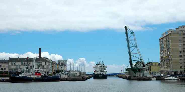 Un cargo sort du port de Saint-Nazaire, s'engage dans l'écluse sud et passe sous le pont levé.